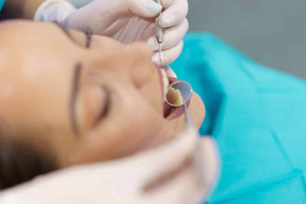 Dentist checking the inside of her patient's teeth with a dental mirror.